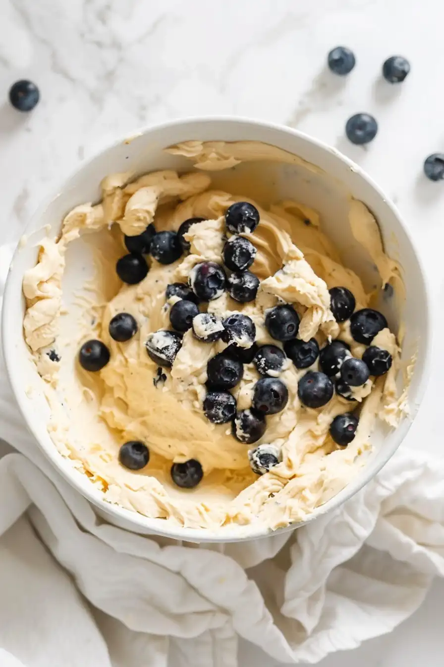 biscuit dough with fresh blueberries in white mixing bowl
