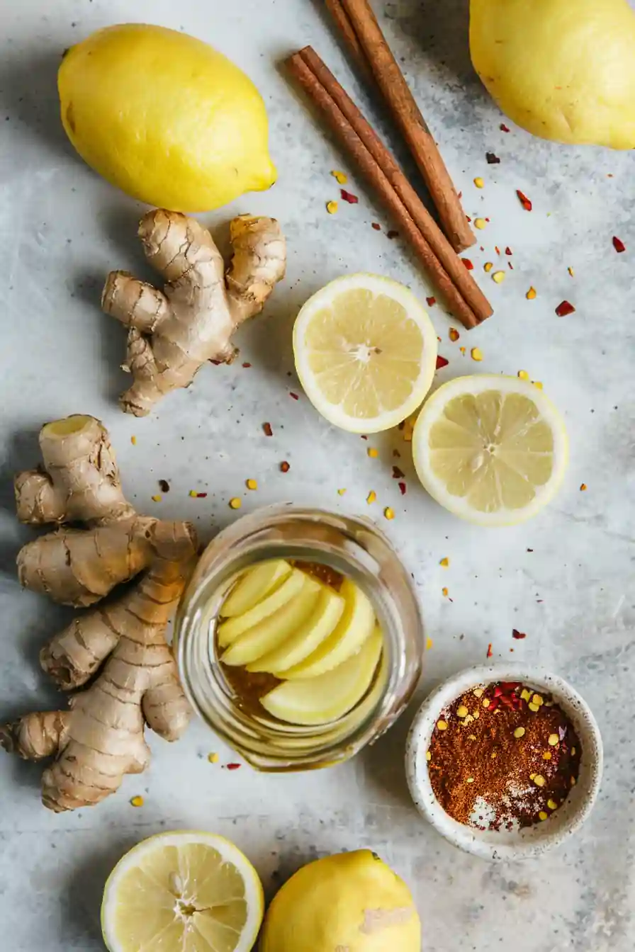 Ginger root, lemon halves, chili flakes, and cinnamon on marble background