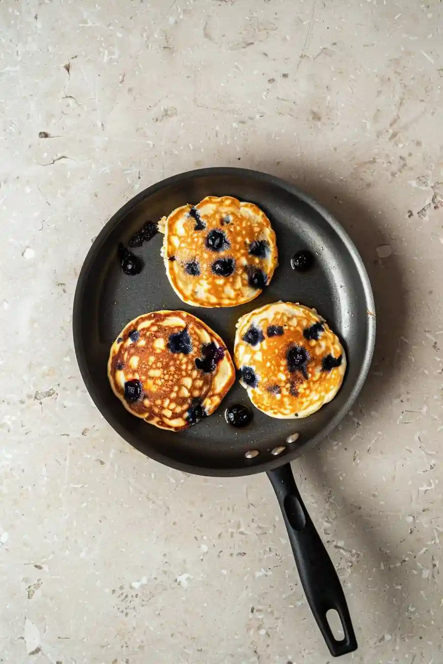 Pancakes with blueberries cooking in a skillet